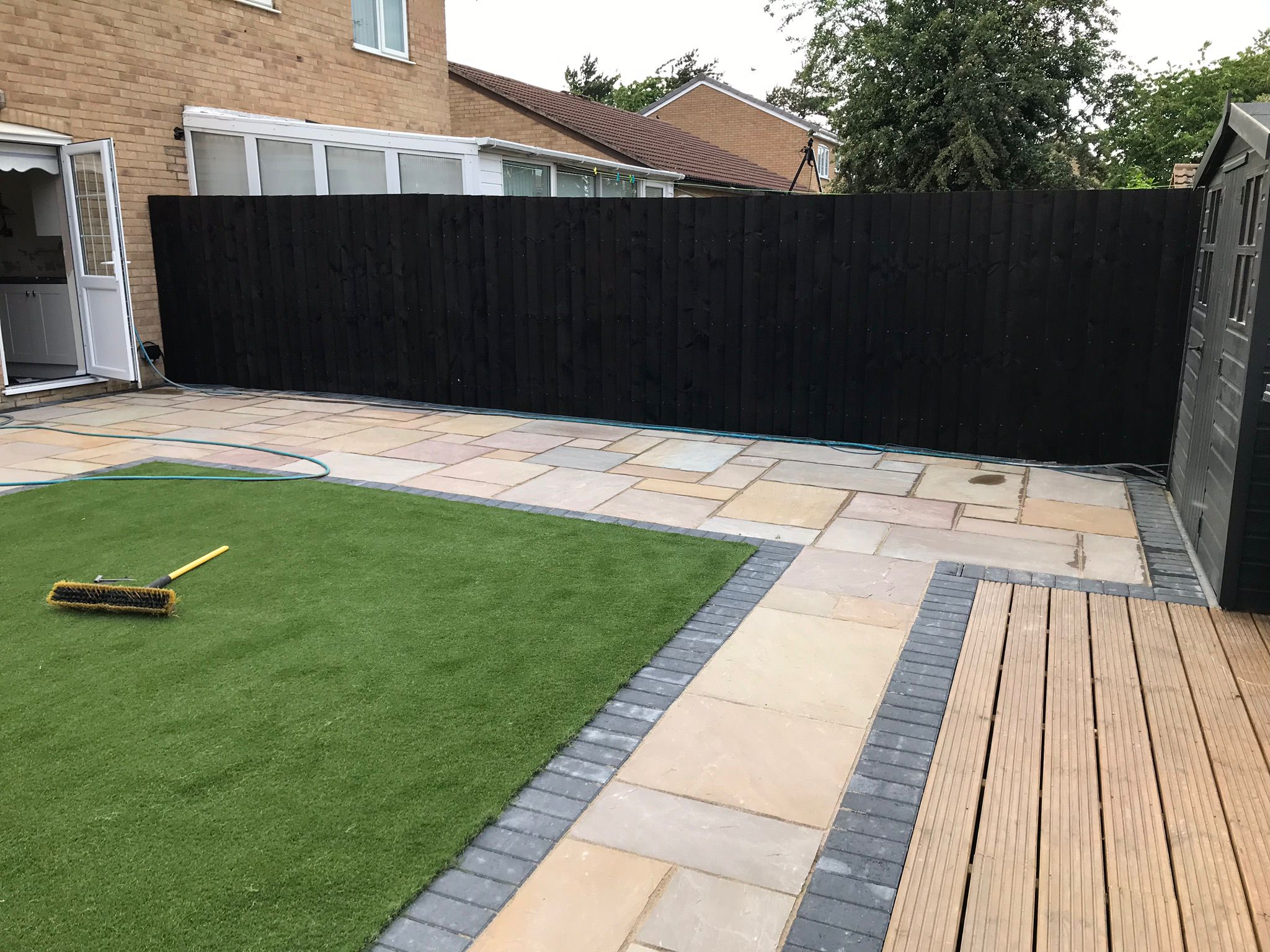 This is a photo of a newly installed patio and path using paving slabs, they are a sand colour with a grey brick edging.